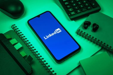 Prag, Çek Cumhuriyeti - 08 18 2025: Merkezde LinkedIn logosunu gösteren bir cep telefonu ile ofis malzemeleri düzenlemesi. LinkedIn, insanları ve şirketleri birbirine bağlayan profesyonel bir ağ..