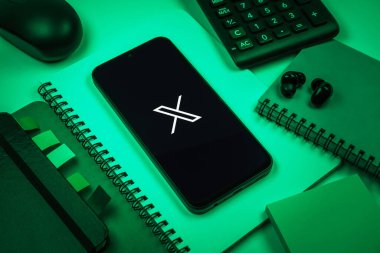 Prag, Çek Cumhuriyeti - 08 18 2025: Merkezinde X logosu sergilenen bir cep telefonu ile ofis malzemeleri düzenlemesi. X, kısa gönderileri ve güncellemeleri paylaşmak için bir platformdur.