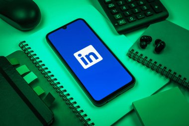 Prag, Çek Cumhuriyeti - 08 18 2025: Merkezde LinkedIn logosunu gösteren bir cep telefonu ile ofis malzemeleri düzenlemesi. LinkedIn, insanları ve şirketleri birbirine bağlayan profesyonel bir ağ..