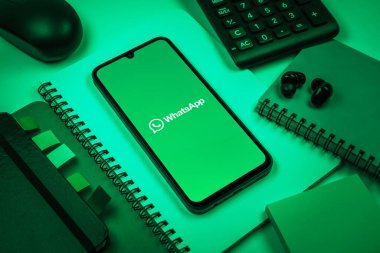 Prag, Çek Cumhuriyeti - 08 18 2025: Ofis malzemelerinin merkezde WhatsApp logosunu gösteren bir cep telefonu ile düzenlenmesi. WhatsApp mesaj, çağrı ve medya göndermek için bir uygulamadır.