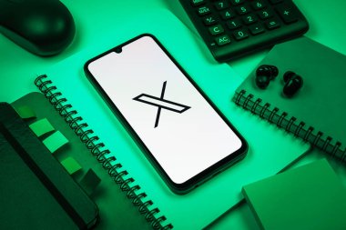 Prag, Çek Cumhuriyeti - 08 18 2025: Merkezinde X logosu sergilenen bir cep telefonu ile ofis malzemeleri düzenlemesi. X, kısa gönderileri ve güncellemeleri paylaşmak için bir platformdur.