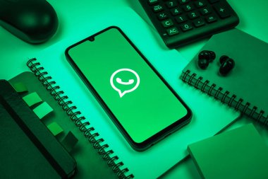 Prag, Çek Cumhuriyeti - 08 18 2025: Ofis malzemelerinin merkezde WhatsApp logosunu gösteren bir cep telefonu ile düzenlenmesi. WhatsApp mesaj, çağrı ve medya göndermek için bir uygulamadır.