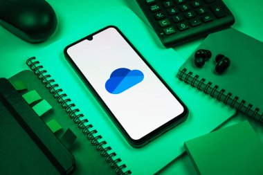 Prag, Çek Cumhuriyeti - 08 18 2025: Merkezde OneDrive logosunu gösteren bir cep telefonu ile ofis malzemeleri düzenlemesi. OneDrive dosyaları kaydetmek ve paylaşmak için bir bulut depolama platformudur.