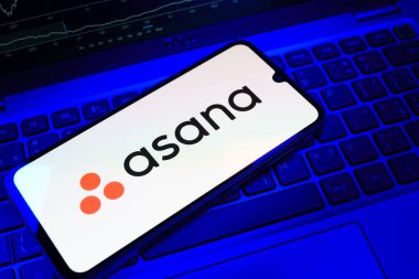 Prag, Çek Cumhuriyeti - 08 18 2025: Klavyede bir cep telefonu Asana logosu sergiler. Asana görev yönetimi ve takım işbirliği için bir platformdur..