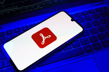 Prag, Çek Cumhuriyeti - 08 18 2025: Klavyede bir cep telefonu Acrobat Reader logosu sergiler. Acrobat Reader, PDF belgelerini görüntülemek ve yönetmek için bir platformdur.