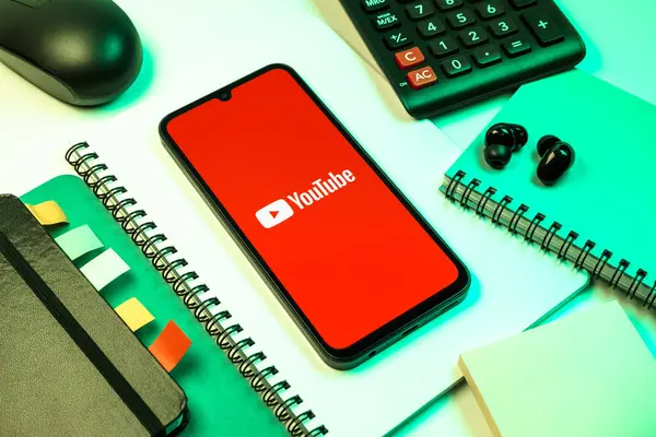 Prag, Çek Cumhuriyeti - 08 18 2025: Merkezde Youtube logosu sergilenen bir cep telefonu ile ofis malzemeleri düzenlemesi. Youtube dünya çapında videoları izlemek ve paylaşmak için bir platform.