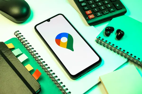 Prag, Çek Cumhuriyeti - 08 18 2025: Merkezde Google Maps logosunu gösteren bir cep telefonu ile ofis malzemeleri düzenlemesi. Google Maps haritalar, navigasyon ve konum hizmetleri için bir platformdur.
