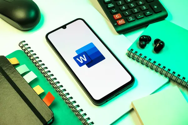 Prag, Çek Cumhuriyeti - 08 18 2025: Merkezinde Word logosu sergilenen bir cep telefonu ile ofis malzemeleri düzenlemesi. Word belge yaratmak ve düzenlemek için bir yazılımdır..