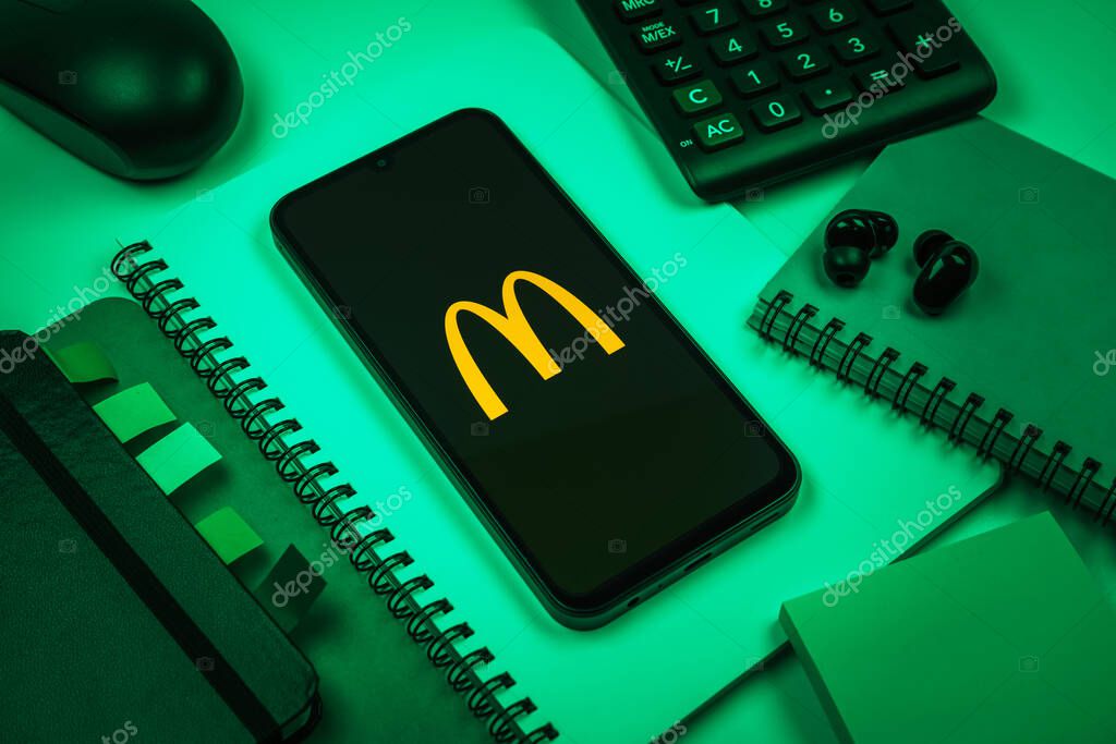 Prague, Czechia - 08 18 2025: An arrangement of office supplies with a mobile phone in the center displaying McDonalds logo. McDonalds is a fast-food chain serving burgers, fries, and more.