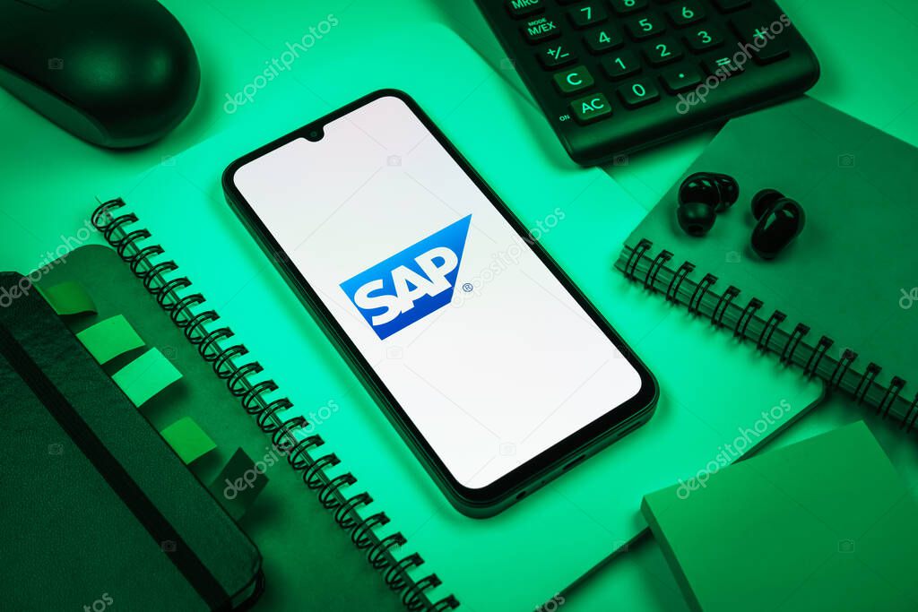 Prague, Czechia - 08 18 2025: An arrangement of office supplies with a mobile phone in the center displaying SAP logo. SAP is a software company providing enterprise applications and solutions.