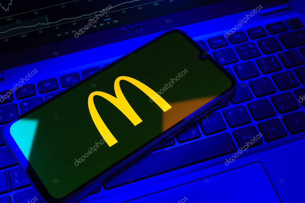 Prague, Czechia - 08 18 2025: A mobile phone on a keyboard displays McDonalds logo. McDonalds is a fast-food chain serving burgers, fries, and more.