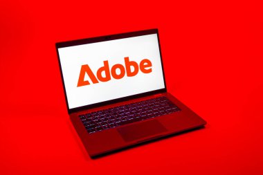 Prag, Çek Cumhuriyeti - 08 12 2025: Tek bir arkaplanda Adobe logosunu gösteren dizüstü bilgisayarın yukarıdan görünüşü. Adobe yaratıcı araçlar ve hizmetler sunan bir yazılım şirketidir..