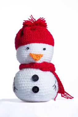 Kırmızı şapkalı ve eşarplı beyaz bir kardan adam. Şapka örüldü ve eşarp örüldü.