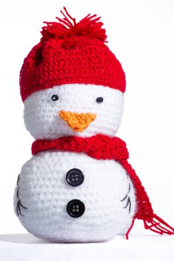 Kırmızı şapkalı ve eşarplı beyaz bir kardan adam. Şapka örüldü ve eşarp örüldü.