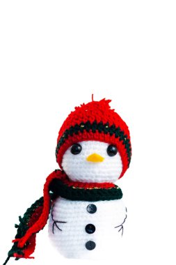 Kırmızı şapkalı ve yeşil eşarplı küçük beyaz bir kardan adam. Şapka örülmüş ve atkı iplikten yapılmış.