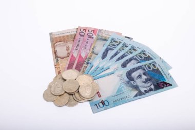 100 'lük banknot da dahil olmak üzere bir yığın bozuk para ve banknot beyaz arka planda yayılıyor.