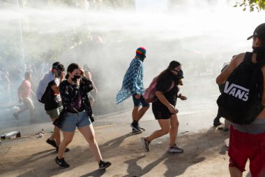 Santiago de Chile - Metropolitan Bölgesi - Şili, 03-08-2021: 8 Mart, Uluslararası Kadınlar Günü. Bir grup insan arka planda minibüsle caddede koşuyor. İnsanlar maske takıyor ve bazıları sırt çantası taşıyor.