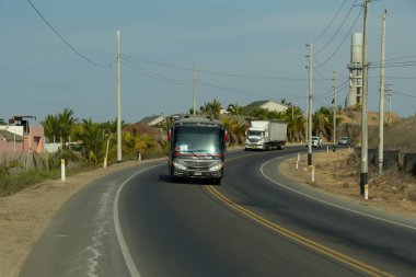 Acapulco, Tumbes, Peru 11-30-2024: Arka planda birkaç araçla birlikte siyah bir kamyon yolda ilerliyor. Yol palmiye ağaçlarıyla kaplı ve tepemizde elektrik hatları var.