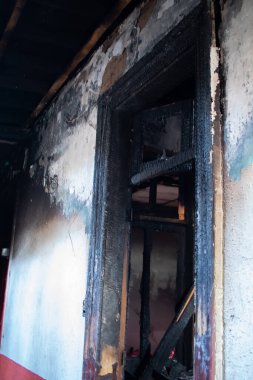 Yanmış bir binanın penceresinden siyah bir duman çıkıyor. Pencere siyah ve duvar beyaz.