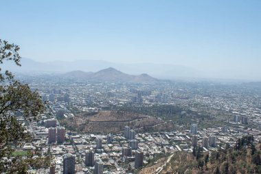 Ortasında büyük bir krater olan bir şehir. Şehir dağlarla çevrili ve gökyüzü açık.