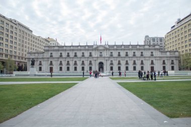 Santiago, Şili - 19 Eylül 2019: önünde bir adamın heykeli olan büyük bir bina. Bina çimenlik bir alan ve kaldırımla çevrilidir. Bölgede dolaşan bir sürü insan var, bazıları el çantası taşıyor..