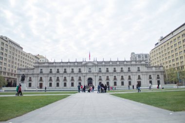 Önünde avlu olan büyük bir bina. İnsanlar avluda dolanıyor..
