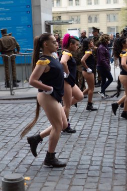 Santiago, Şili - 19 Eylül 2019: Siyah ve sarı elbiseli bir grup kadın kaldırım taşlı bir sokakta dans ediyorlar. Kadınlar beyaz eldiven giyiyorlar ve siyah ve sarı kıyafetler giyiyorlar..