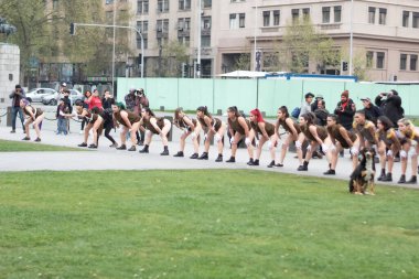 Santiago, Şili - 19 Eylül 2019: Bir grup kadın önlerinde bir köpekle parkta kuyrukta bekliyorlar. Kadınlar kahverengi kıyafetler giyip dans gösterisi yapıyor gibi görünüyorlar..