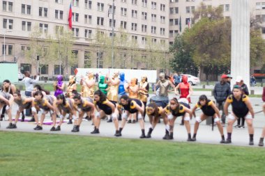 Santiago, Şili - 19 Eylül 2019: Bir grup insan parkta, bazıları kostüm giyiyor. Sahne canlı ve eğlenceli, insanlar birlikte dans ediyor ve egzersiz yapıyor..