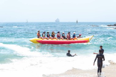 Üzüm bağı, Santiago, Şili - 10 Ocak 2020: Bir grup insan okyanusta sarı ve kırmızı bir saldalar. İnsanlar can yelekleri giyiyorlar ve suda vakit geçirmenin tadını çıkarıyorlar..