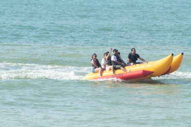Zorritos, Tumbes, Peru - 24 Aralık 2023: Bir grup insan okyanusta iki sarı şişme sala biniyor. Sallar sarı ve kırmızı ve insanlar can yelekleri giyiyor. Sahne canlı ve eğlenceli..