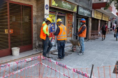 Santiago, Şili - 27 Ekim 2020: Bir grup inşaat işçisi binanın dışında duruyor. İşçilerden biri sıkı bir şapka takıyor.