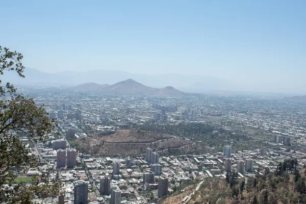 Ortasında büyük bir krater olan bir şehir. Şehir dağlarla çevrili ve gökyüzü açık.