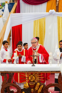 Tumbes, Tumbes, Peru 21-10-2023, Onaylama Ayini: Bir rahip elinde haç olan bir grup insanın önünde duruyor. Rahip kırmızı bir bornoz giyiyor ve mumlarla çevrili. Sahne kutsal ve dindardır.