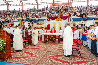 Tumbes, Tumbes, Peru 21-10-2023, Ayin Ayini: Büyük bir kalabalık dini bir etkinlik için stadyumda toplandı. Etkinlik, üzerinde beyaz bir bez olan bir masanın önünde duran bir rahip tarafından yönetiliyor.