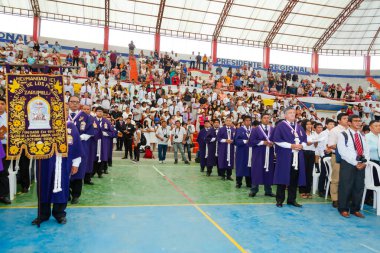 Tumbes, Tumbes, Peru 21-10-2023, Onaylama Ayini: Bir grup insan stadyumda duruyor, bazıları mor cübbe giyiyor. Kalabalık bir geçit töreni ya da tören izliyor.