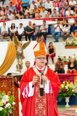 Tumbes, Tumbes, Peru 21-10-2023, Doğrulama Ayini: Bir rahip elinde mikrofonla kalabalığın önünde duruyor. Rahip kırmızı bir bornoz ve beyaz bir yaka giyiyor. Kalabalık rahibi dikkatle izliyor.