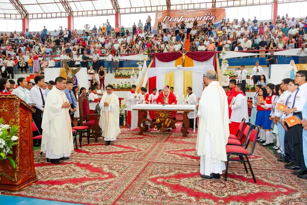 Tumbes, Tumbes, Peru 21-10-2023, Ayin Ayini: Büyük bir kalabalık dini bir etkinlik için stadyumda toplandı. Etkinlik, üzerinde beyaz bir bez olan bir masanın önünde duran bir rahip tarafından yönetiliyor.