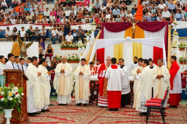 Tumbes, Tumbes, Peru 21-10-2023, Doğrulama Ayini: Bir grup rahip bir masanın etrafında toplanmış, büyük bir kalabalık izliyor. Sahne saygılı ve ağırbaşlıdır.