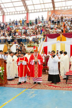 Tumbes, Tumbes, Peru 21-10-2023, Doğrulama Ayini: Kırmızı cüppeli bir grup insan kalabalığın önünde duruyor. Adamlardan biri sopa tutuyor.