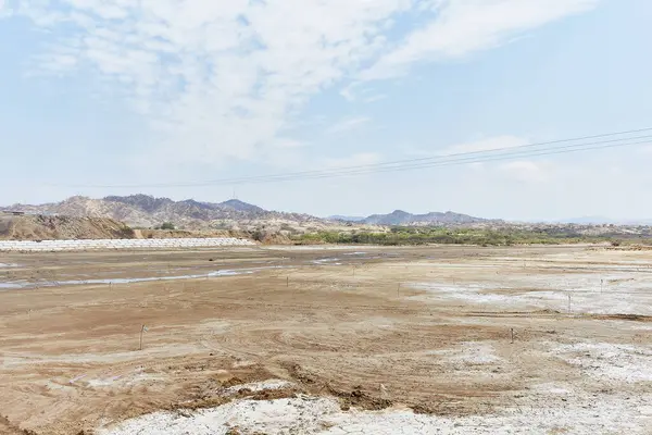 Birkaç kuşun gökyüzünde uçtuğu çorak bir çöl manzarası. Gökyüzü açık ve mavidir, ve güneş parlıyor. Boşluk ve yalnızlık kavramı