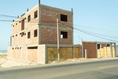 Bir sürü penceresi olan büyük bir tuğla bina inşa ediliyor. Bina bir sürü elektrik hattı olan bir caddede.