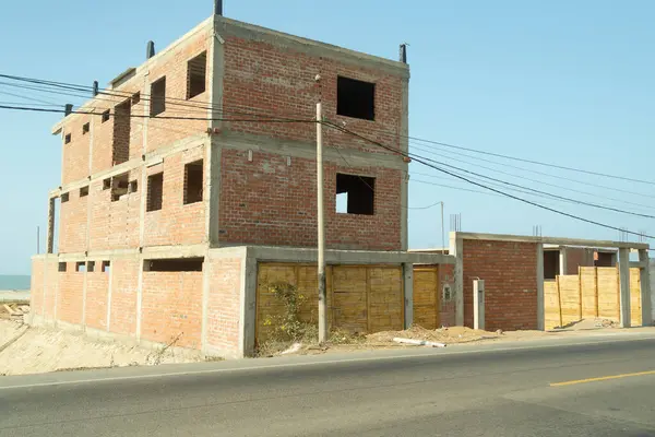 Bir sürü penceresi ve bir kaç boş penceresi olan büyük bir tuğla bina. Bina yapım aşamasında.