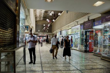 Santiago de Chile, Şili, 04-02-2021: Maskeli bir adam kalabalık bir alışveriş merkezinde yürüyor. Alışveriş merkezinde bir sürü insan var, bazıları maske takıyor.