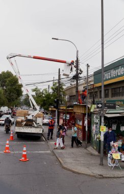 Santiago de Chile, Şili, 04-02-2021 kaldırımda elinde vinç olan bir kamyonun yanında bir adam duruyor. Bölgede dolaşan birkaç kişi var ve yakınlarda da birkaç araba var. Sahne yoğun ve hareketli görünüyor.