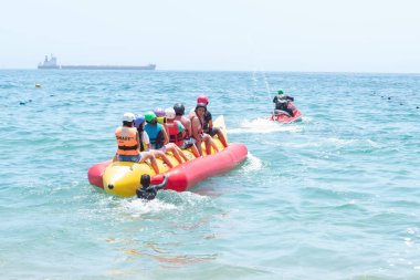 Vina del Mar - Şili, 10-01-2020: Bir grup insan okyanusta sarı bir tekneye biniyor. Tekne sarı ve kırmızı ve yeşil ceketli bir adam tarafından kullanılıyor. Teknedeki insanlar can yelekleri ve kasklar giyiyorlar.