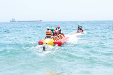 Vina del Mar - Şili, 10-01-2020: Bir grup insan okyanusta sarı ve kırmızı bir tekneye biniyor. Tekne insanlarla dolu ve suda hareket ediyor.