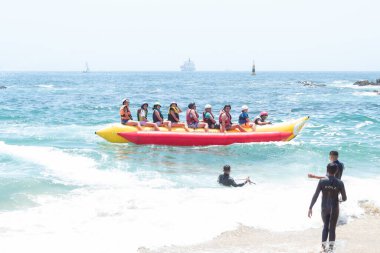 Vina del Mar - Şili, 10-01-2020: Bir grup insan okyanusta sarı ve kırmızı bir sala biniyor. İnsanlar can yelekleri giyiyor ve gezinin tadını çıkarıyorlar.