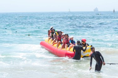 Vina del Mar - Şili, 10-01-2020: Bir grup insan okyanusta sarı şişme bir sala biniyor. Sal, dalgıç kıyafetli bir adam da dahil olmak üzere insanlarla dolu. Sahne canlı ve eğlenceli, herkes yolculuğun tadını çıkarıyor.