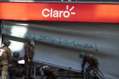 Santiago de Chile, Şili, 20-10-2019: Bir grup adam kırık bir kapıyı onarmaya çalışıyor. Manzara gergin ve kaotik.